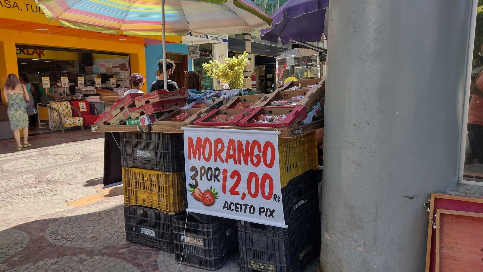 Banca de morangos na calçada com cartaz “Morango 3 por 12,00 – Aceito Pix”
